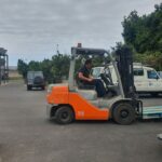 Obrero subido a una carretilla haciendo trabajos de traslado de cajas.