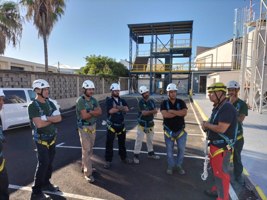 Grupo de alumnos con cascos blancos y escuchando al formador