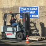 Operario vestido con una camiseta negra y subido a una máquina para aprender a mover pallets