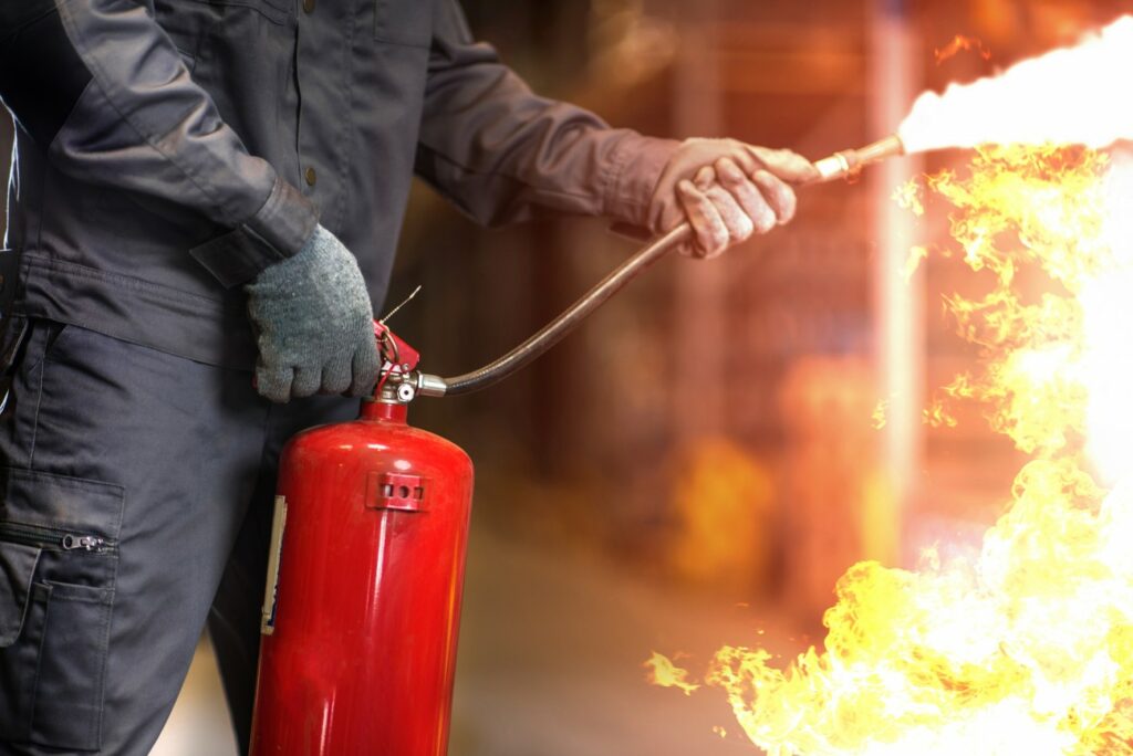 Alumno con un extintor en las manos rojo y aprendiendo como apagar un fuego.