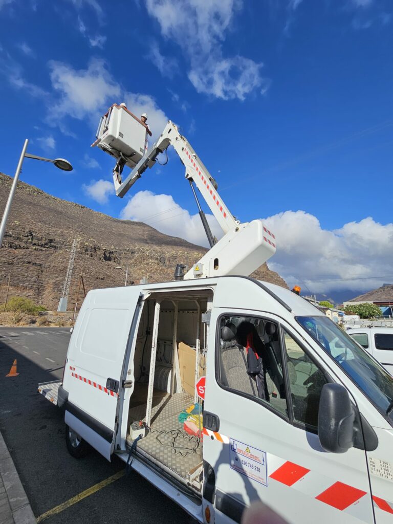 Un camión Grúa blanco con operarios arreglando las farolas